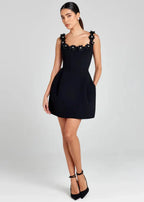 Robe courte noire sans manches avec broderies de fleurs blanches, en tissu léger, parfaite pour des soirées élégantes.