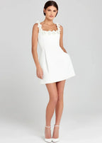 Robe courte noire sans manches en tissu léger, ornée de broderies de fleurs blanches pour une soirée élégante.