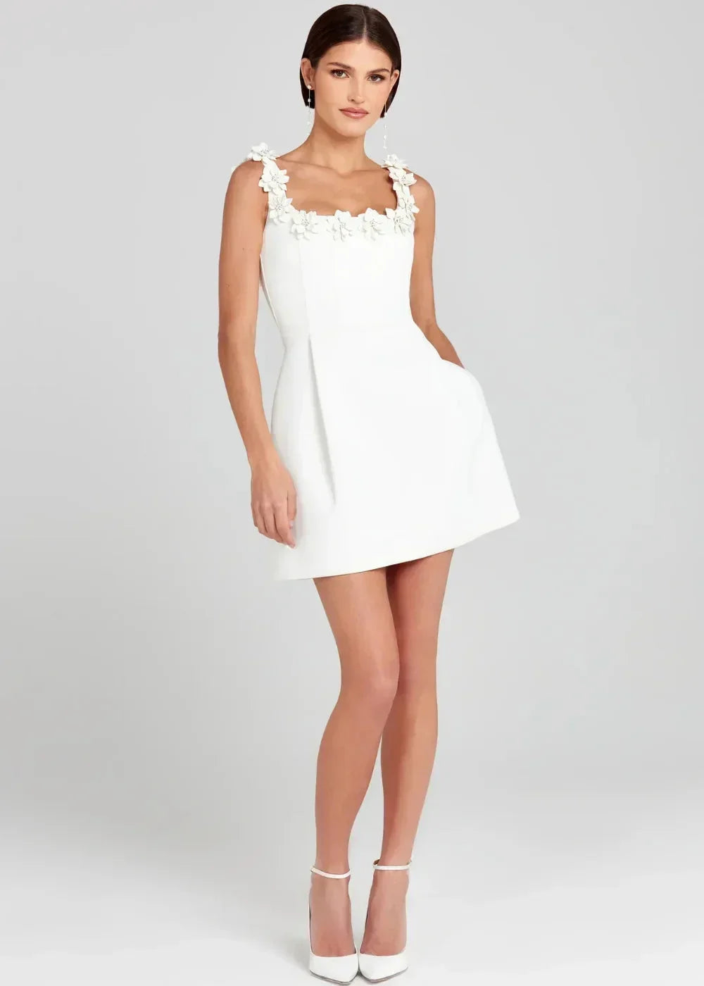 Robe courte noire sans manches en tissu léger, ornée de broderies de fleurs blanches pour une soirée élégante.