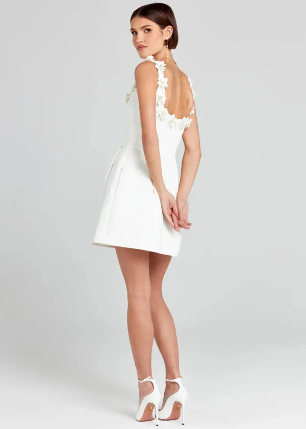 Robe courte noire sans manches, brodée de fleurs blanches, en tissu léger idéale pour une soirée élégante.