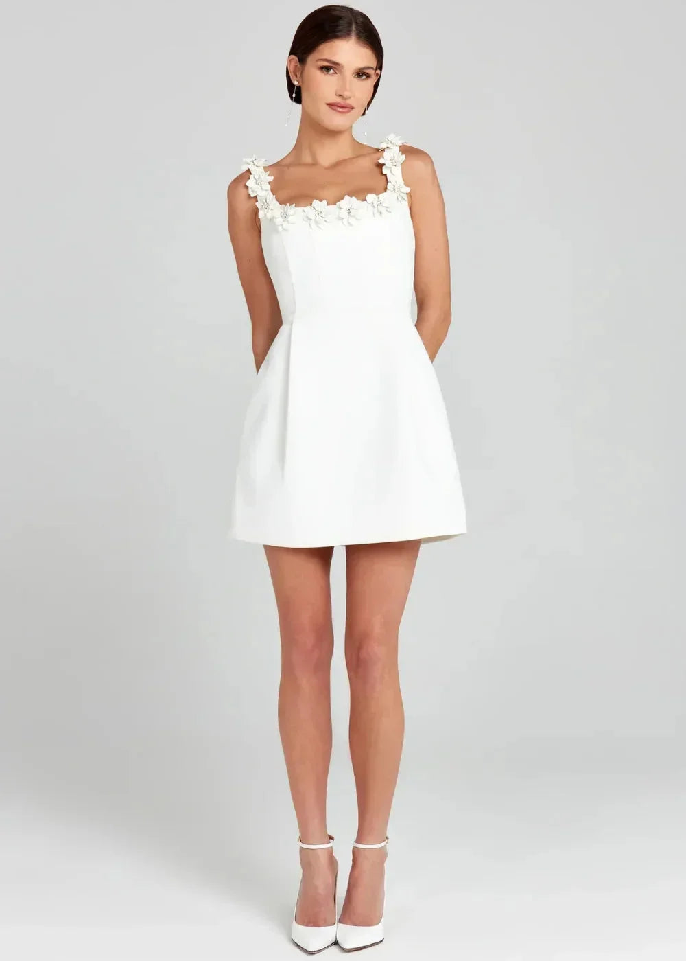 Robe courte noire sans manches avec broderies de fleurs blanches, en tissu léger, idéale pour les soirées élégantes.