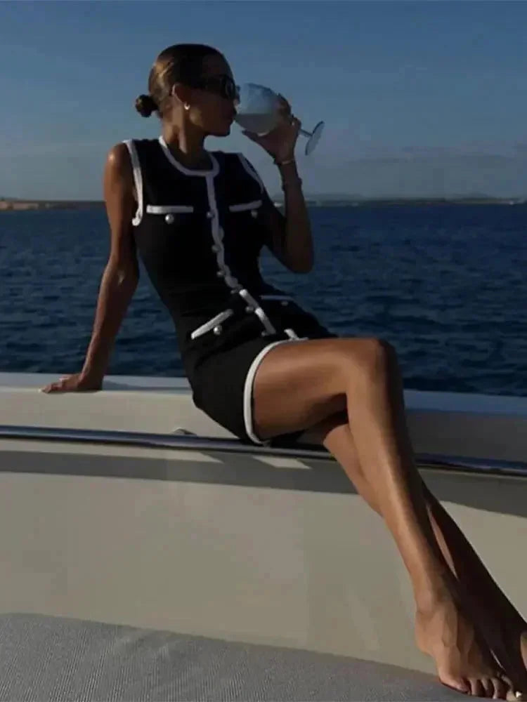 Robe courte noire sans manches avec détails en perles et bordure blanche, en tissu léger, design ajusté parfait pour un…