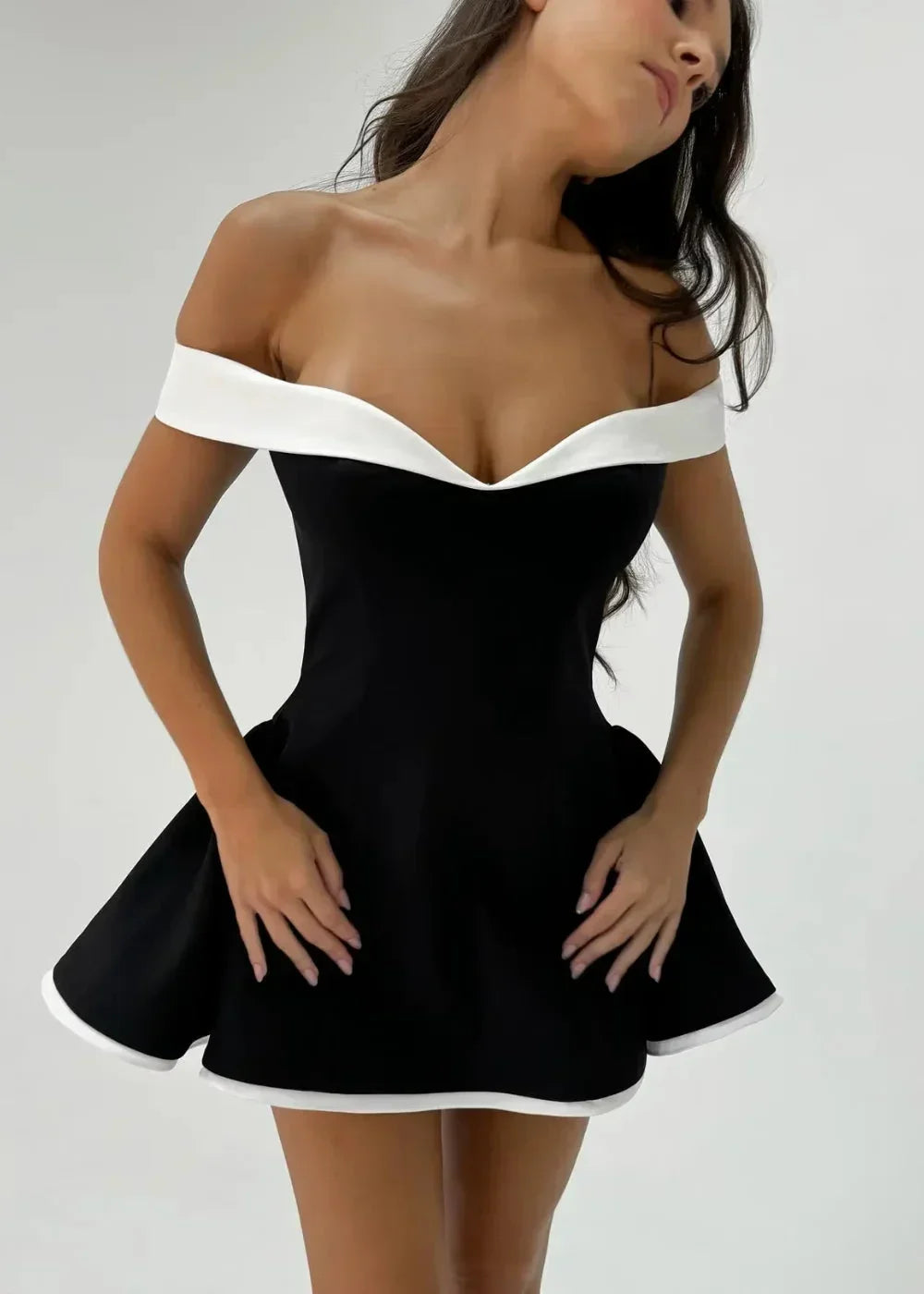 Robe courte noire à épaules dénudées, avec un bord blanc et une jupe évasée, parfaite pour des soirées élégantes.