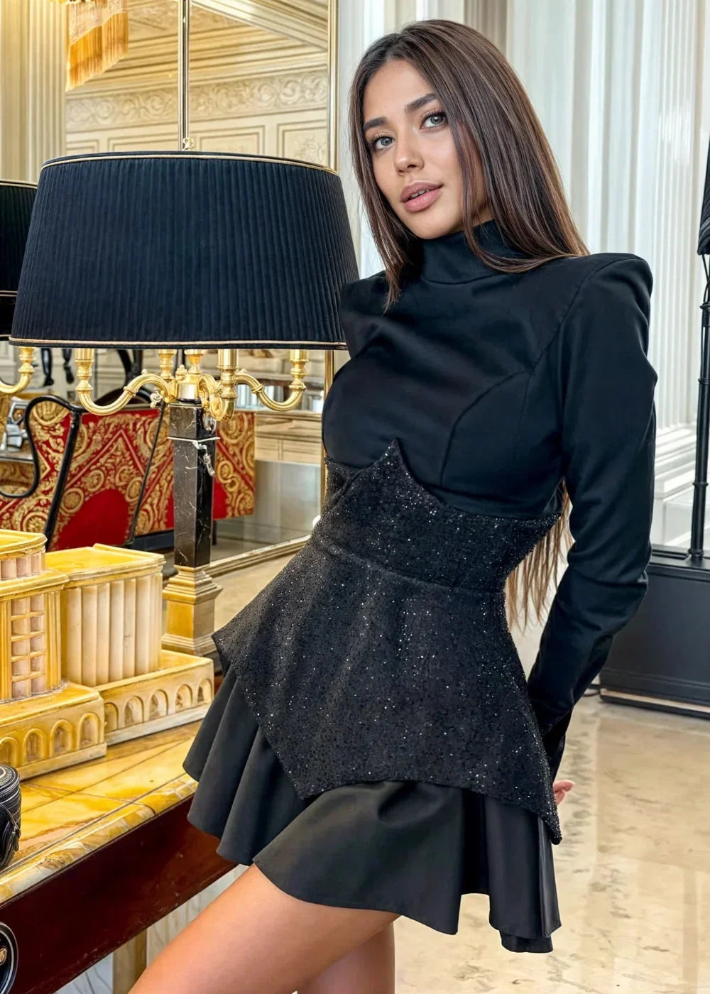 Robe courte noire à peplum avec sequins, manches longues, en tissu doux et léger, idéale pour les soirées élégantes.