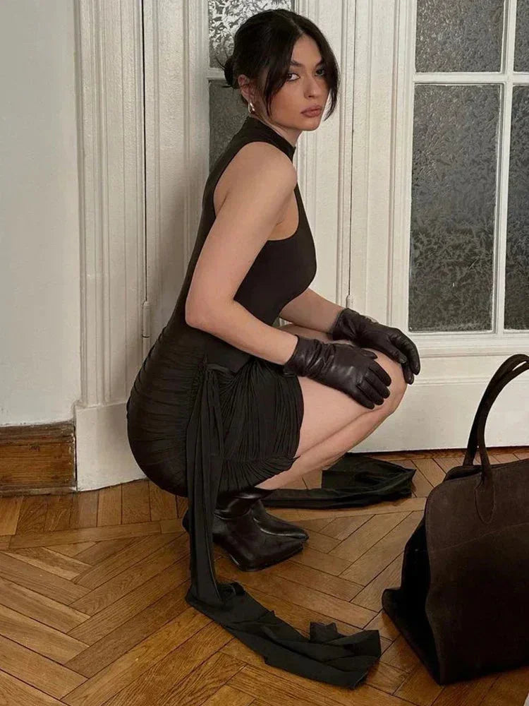 Robe courte noire sans manches, col montant, coupe ajustée en tissu léger pour une allure élégante lors des soirées.