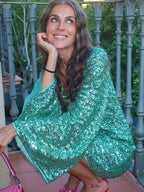 Robe courte en sequins avec col plongeant et manches évasées, idéale pour les soirées clubbing et les occasions festives.