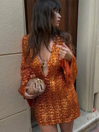Robe courte pailletée à col plongeant, manches évasées, en tissu brillant parfait pour les soirées clubbing.
