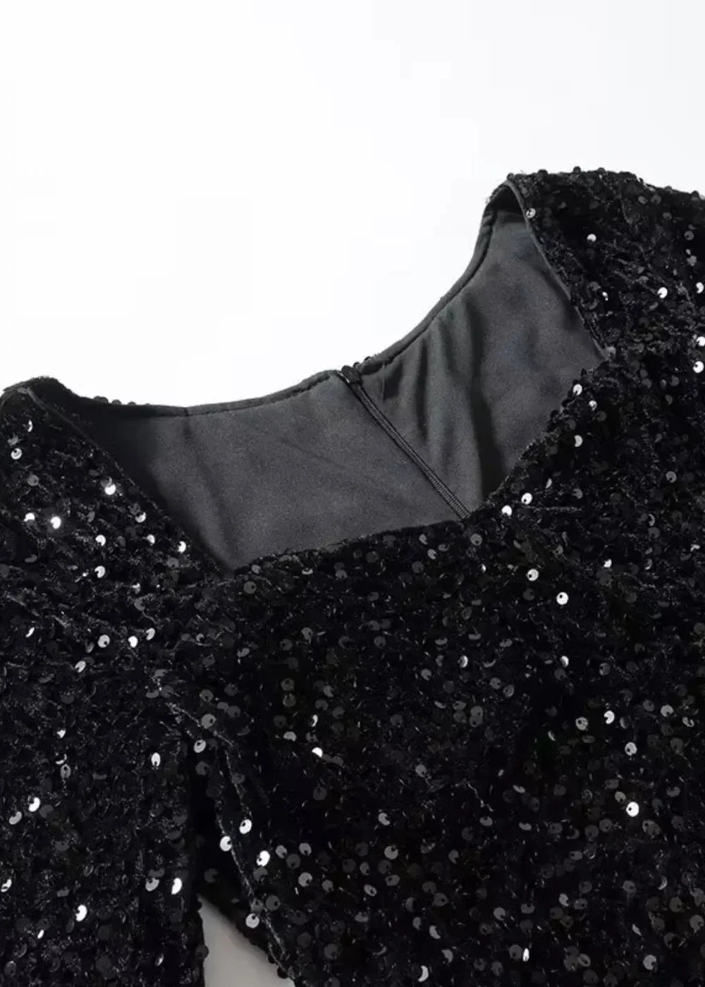 Robe courte noire à paillettes, manches longues, col en cœur, coupe ajustée, idéale pour les soirées festives.