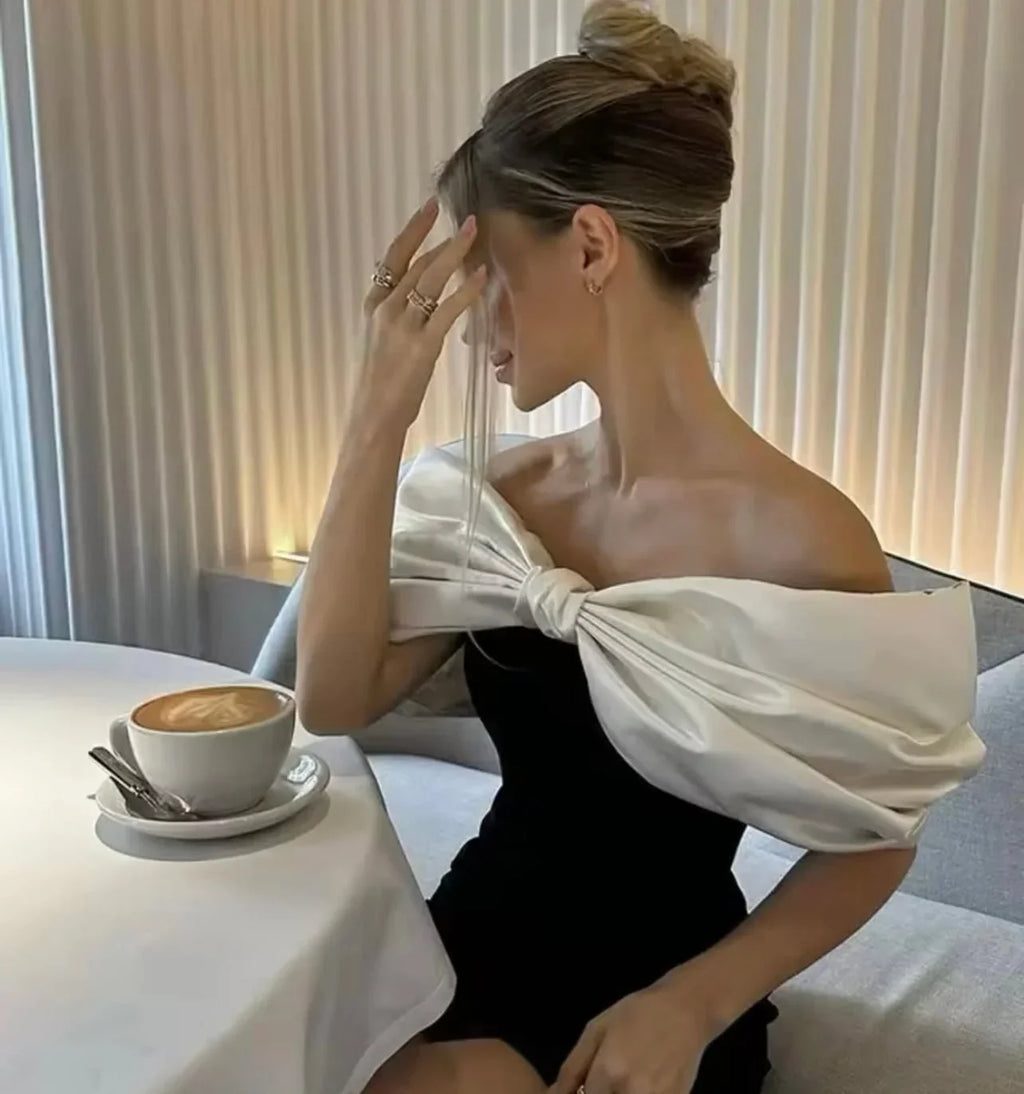 Robe courte à épaules dénudées avec nœud, en tissu léger, idéale pour une soirée cocktail élégante.