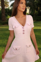 Robe courte rose en coton avec boutons, poches, manches courtes et col V, idéale pour l'été avec sa coupe ajustée.