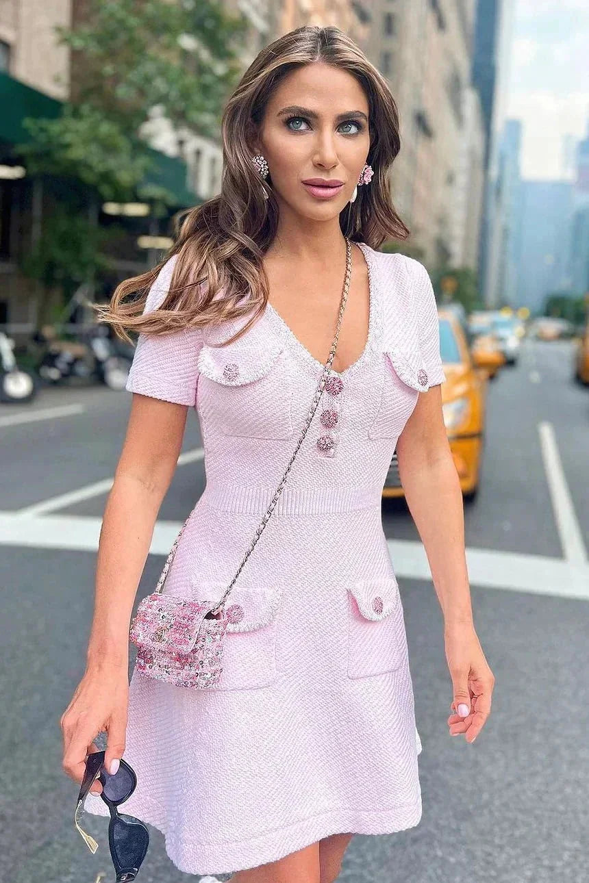 Robe courte rose avec boutons, poches et manches courtes, col V, en tissu léger, coupe ajustée pour les journées d'été.