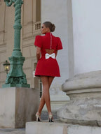 Robe courte rouge en tissu léger avec boutons décoratifs, dos ouvert et nœud, idéale pour les soirées.