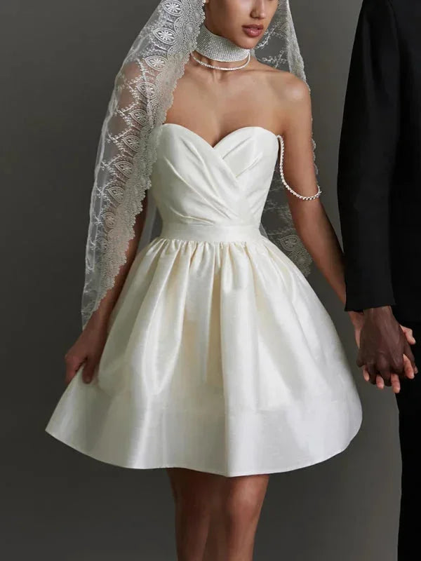 Robe courte satinée avec bretelles ornées de strass, col en cœur et dos nu, disponible en plusieurs couleurs.