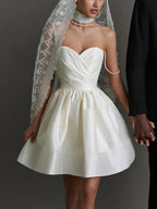 Robe courte satinée avec bretelles ornées de strass, col en cœur et dos nu, disponible en plusieurs couleurs.