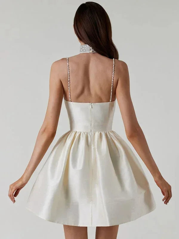 Robe courte satinée à bretelles ornées de strass, col cœur et dos nu, disponible en plusieurs couleurs.