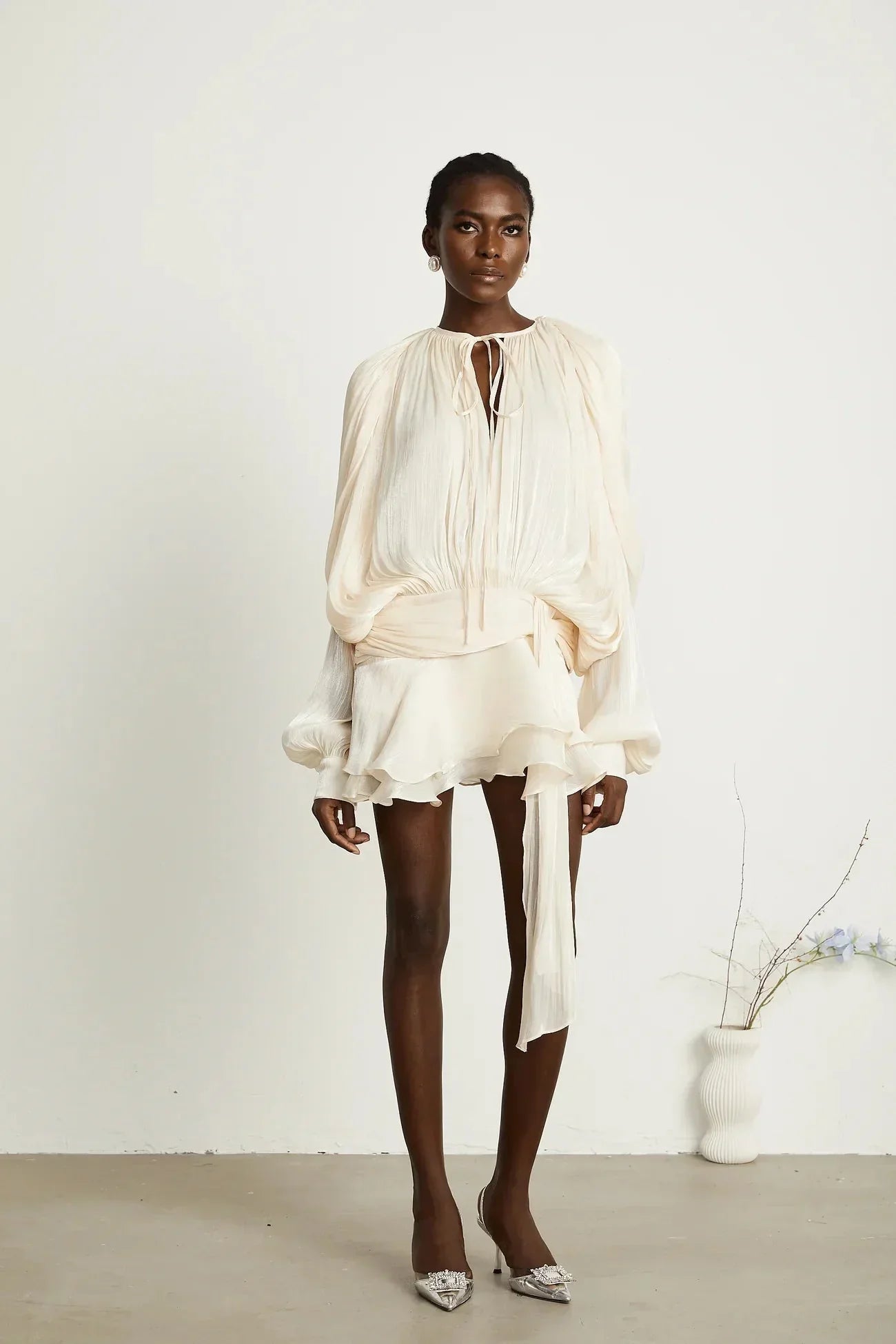 "Robe courte satinée fluide avec nœuds aux manches longues, disponible en plusieurs couleurs, idéale pour les soirées."