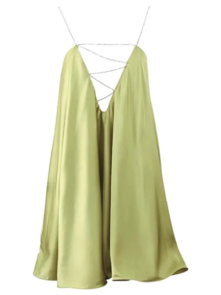 Robe courte satinée fluide avec chaînes décoratives, idéale pour soirées, mettant en avant un drapé élégant et léger.