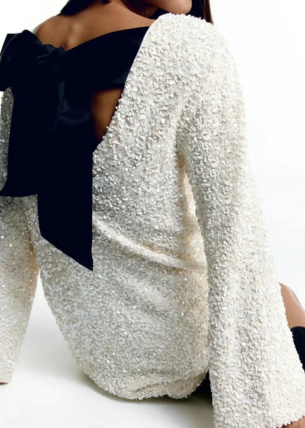 "Robe courte blanche à manches longues, col chic, en tissu brillant, idéale pour les soirées élégantes."