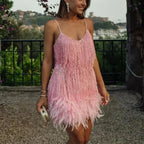 Robe courte en sequins avec plumes délicates et bretelles fines, parfaite pour une soirée cocktail élégante.