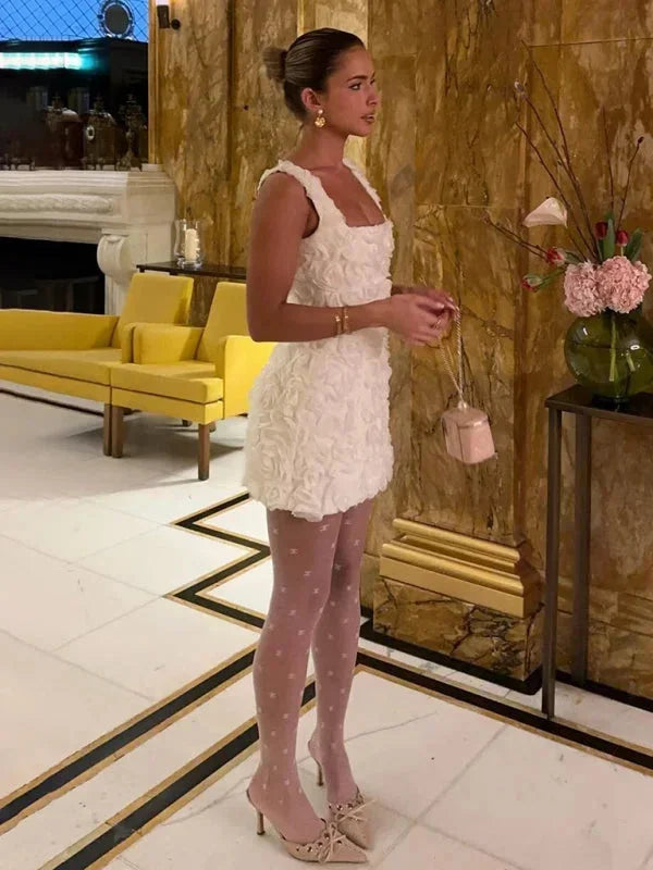 Robe courte à bretelles avec motif floral, fabriquée en tissu texturé pour un style léger et décoratif.