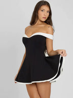 Robe courte évasée noire à bordure blanche, épaules dénudées, en tissu léger, coupe ajustée pour un look élégant.