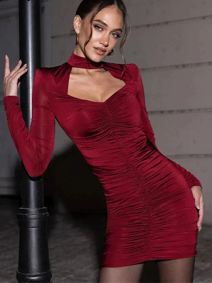 Robe courte en velours rouge avec découpe, col en V et manches longues, idéale pour une soirée élégante.
