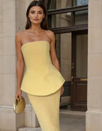 Top bustier jaune en tissu léger avec basque, accompagné d'une jupe côtelée pour un look élégant et féminin.