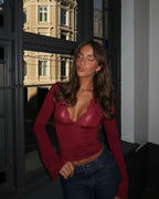 Top bordeaux en dentelle avec col V et manches évasées, adapté pour des occasions élégantes.