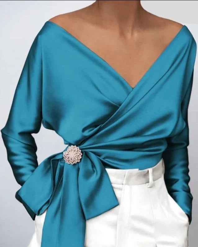 Top femme portefeuille rose avec nœud et broche, design moderne et coupe ajustée.