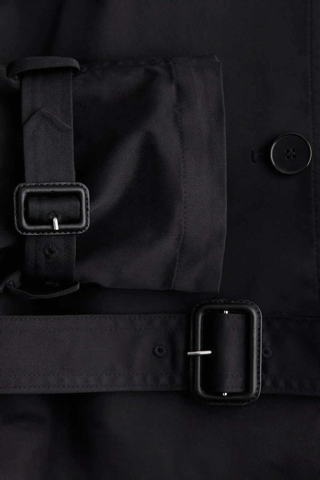 Trench-coat femme avec col montant, ceinture nouée et tissu résistant, adapté aux conditions météorologiques changeantes.