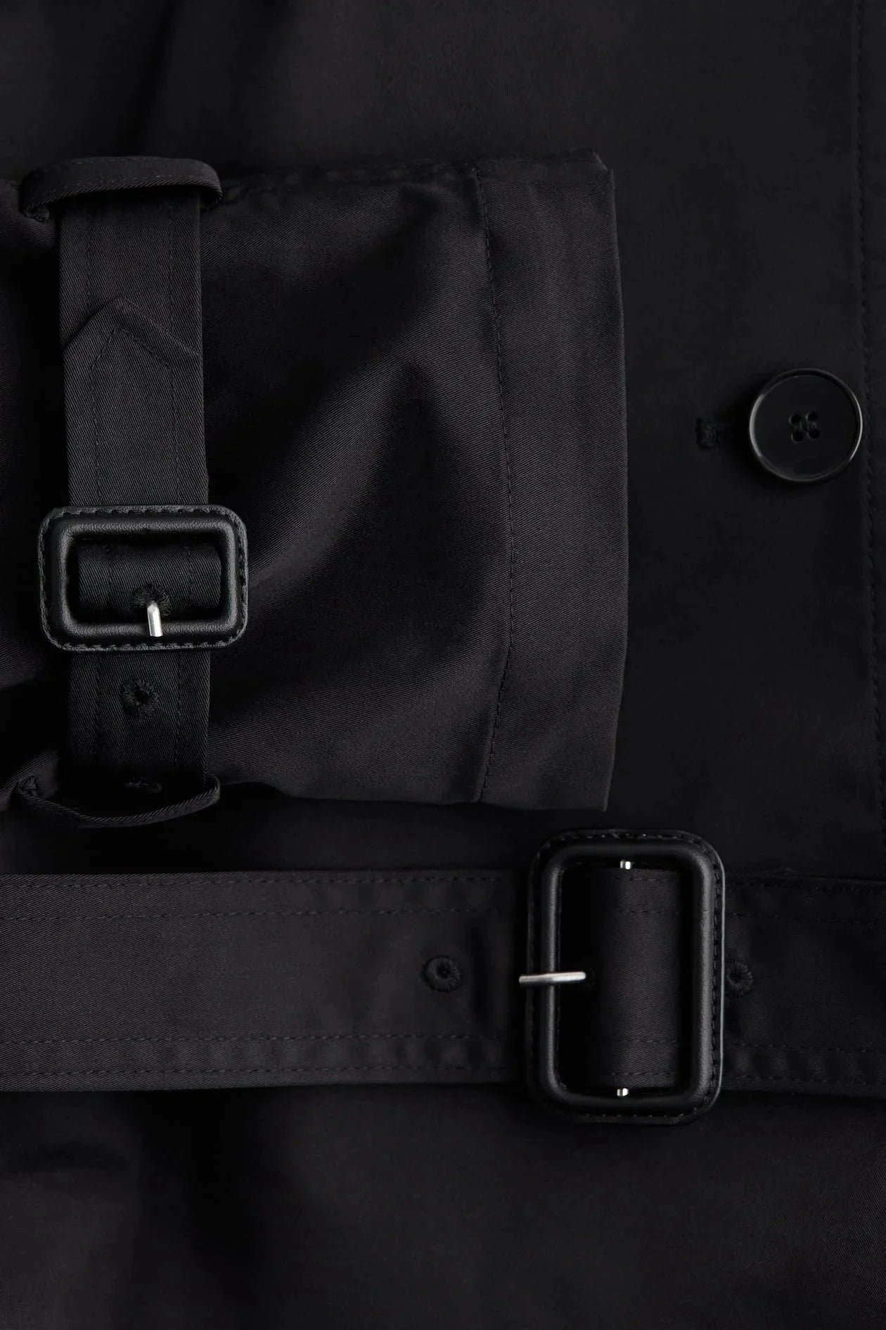 Trench-coat femme avec col montant, ceinture nouée et tissu résistant, adapté aux conditions météorologiques changeantes.