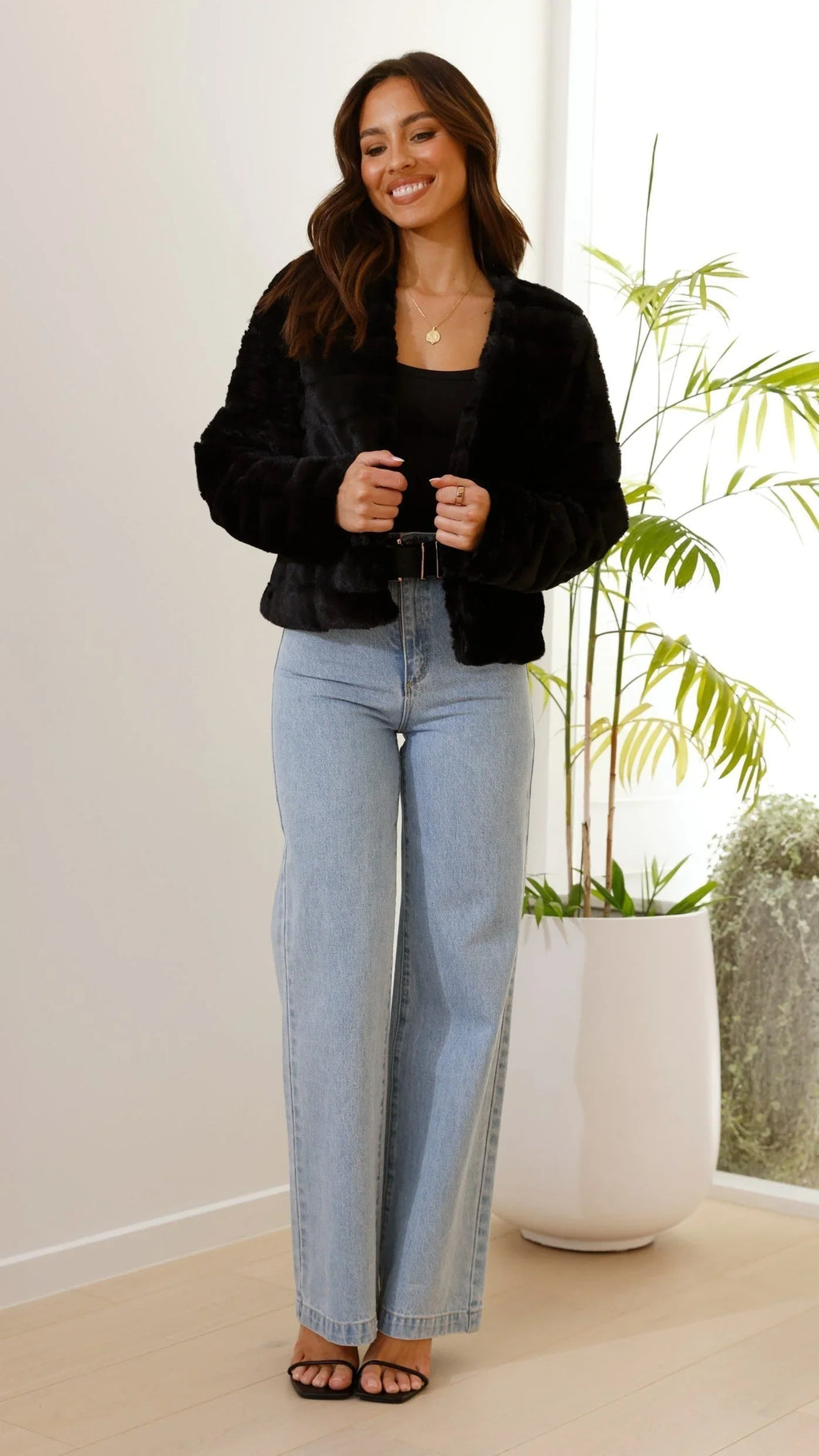 Veste courte femme en fausse fourrure noire avec col ouvert, parfaite pour les journées fraîches.