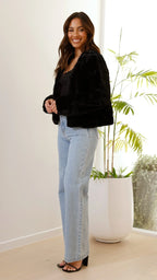 Veste courte femme en fausse fourrure noire avec col ouvert, parfaite pour un look décontracté et superposé.