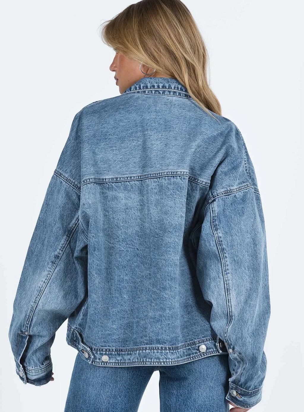 Veste en jean bleu pour femme, coupe ample, style rétro, avec poches poitrine et fermeture à boutons.