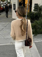 Veste femme beige courte en tweed avec boutons, parfaite pour des tenues décontractées ou habillées.