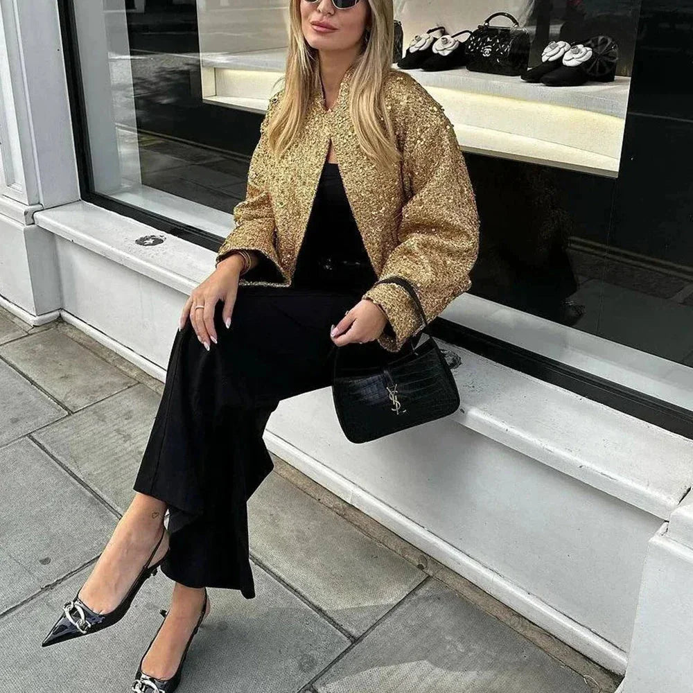 Veste femme chic à paillettes, en tissu doux, avec une coupe ajustée et des embellissements scintillants sur les manches.