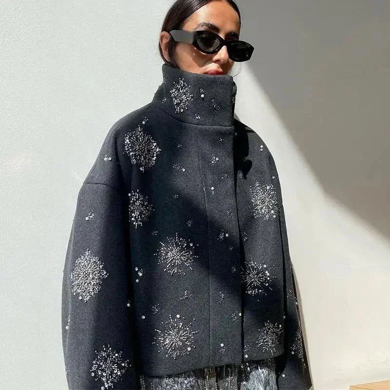 Graue Veste für Frauen mit Stehkragen, Broderie-Details und lässigen Fledermausärmeln aus leichtem Stoff.