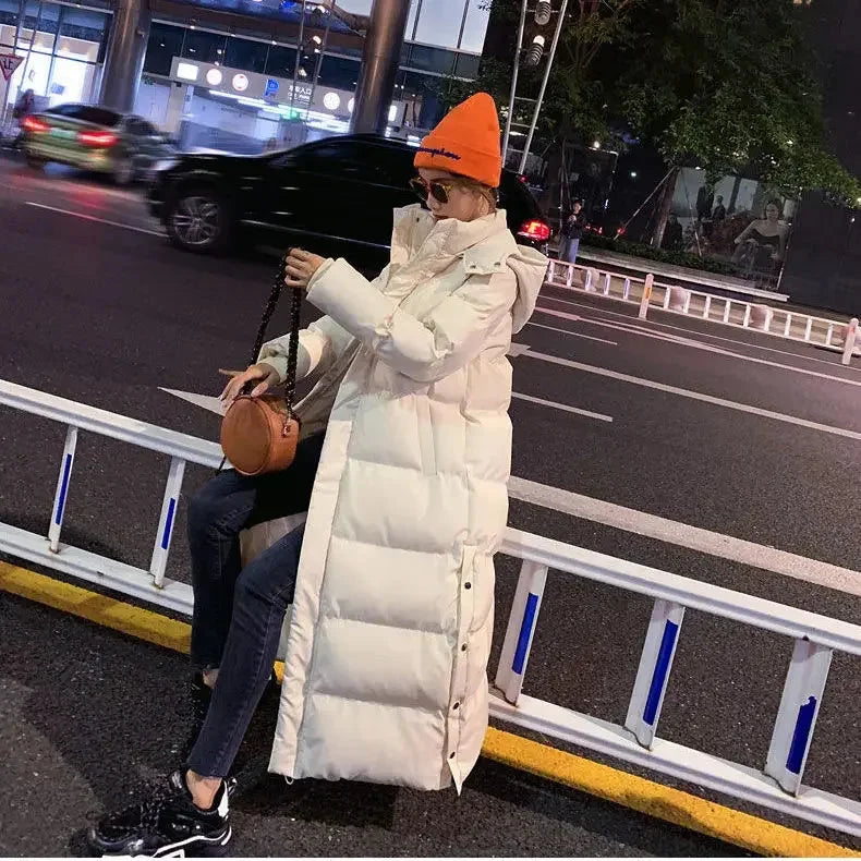 Doudoune longue blanche pour femme, avec capuche amovible, en matériau chaud et déperlant.