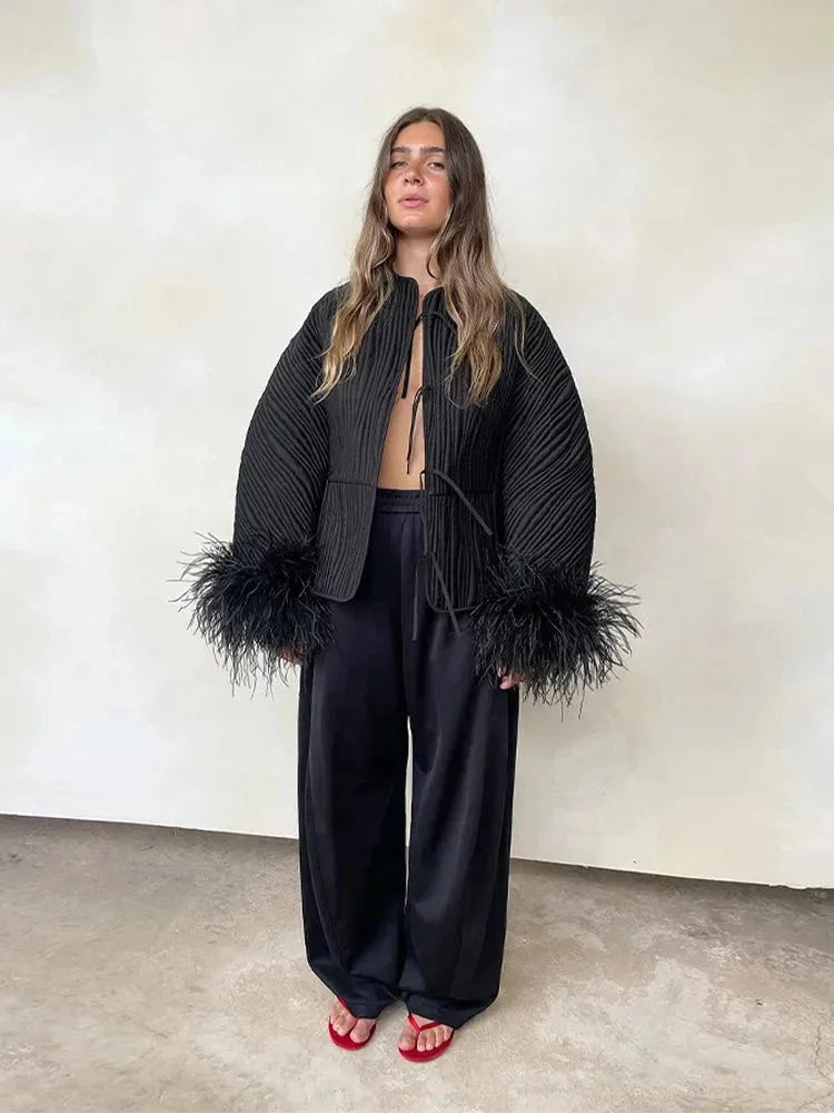 Veste noire femme en viscose douce avec poignets en plumes pour un style élégant.
