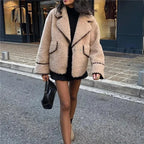 Veste teddy femme beige avec coutures noires, en matériau doux, adaptée pour les journées fraîches.