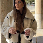 Veste teddy femme beige oversize avec accents noirs, en matériau doux, parfaite pour des looks décontractés.