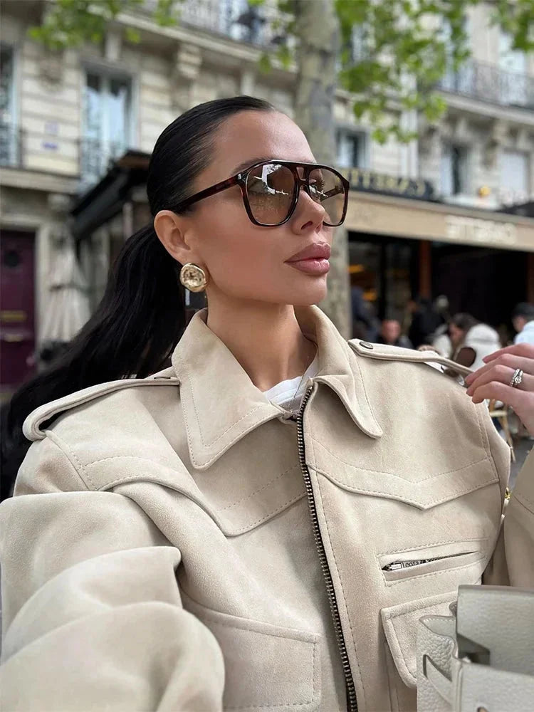 Veste trench courte beige pour femme avec col à revers et ceinture, en tissu léger et résistant.